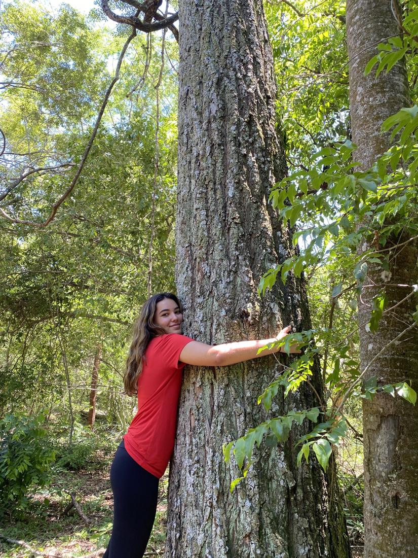 Una persona abraza el tronco de un árbol del monte nativo
